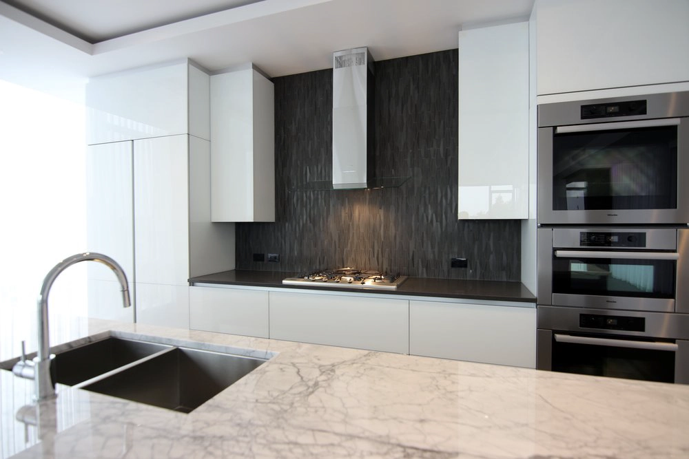High-end cooktops & ovens installation with built-in refrigerator, gas cooktop, and chimney hood in Redfern penthouses, Westmount.
