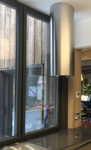 Custom circular island hood installation in high ceiling kitchen